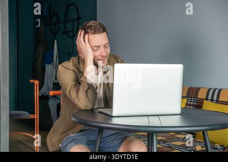 Man sitting at table using laptop computer at home and smiling during online communication. Online conversation, video call with family or friends Stock Photo