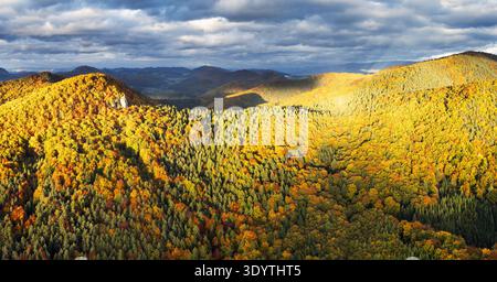 Scenic autumn sunset panorama in Strazovske vrchy in Slovakia with dramatic sunlight clouds on sky on colorful leaves on trees in forests on stone and Stock Photo