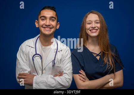 Diverse medical team members, a male doctor and female nurse, smiling confidently in uniform on a blue background Stock Photo