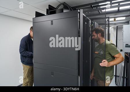 Two technicians installing and inspecting servers in a modern data center rack room for network infrastructure Stock Photo
