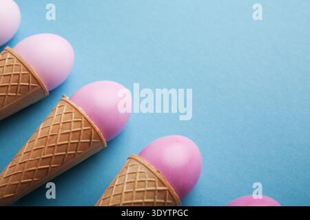 Pink easter eggs in waffle cones on blue background Stock Photo