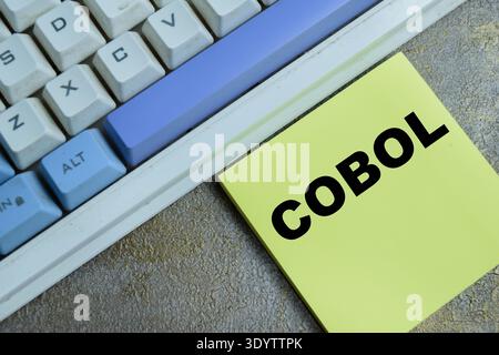 Concept of COBOL - Common-Business Oriented Language programming write on sticky notes isolated on Wooden Table. For legacy system maintenance, mainte Stock Photo