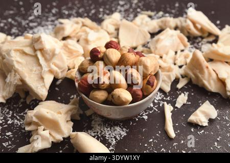 Crushed white chocolate pieces and hazelnuts on gray background Stock Photo
