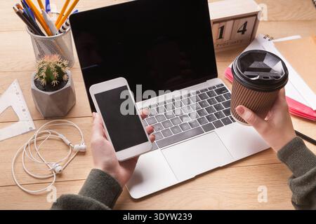 Closeup of female hands holding smartphone and coffee cup Stock Photo