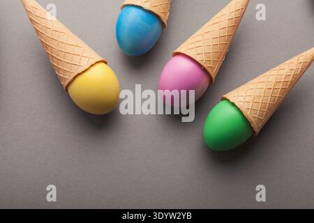 Colorful easter eggs in waffle cones on gray background Stock Photo