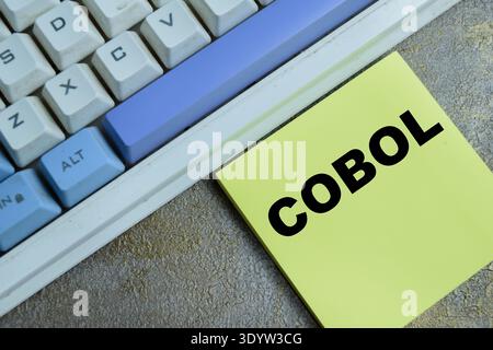 Concept of COBOL - Common-Business Oriented Language programming write on sticky notes isolated on Wooden Table. For legacy system maintenance, mainte Stock Photo