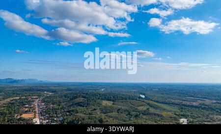 A breathtaking drone perspective captures a rugged highland ridge surrounded by dense forest, with brilliant white clouds contrasting against the vibr Stock Photo