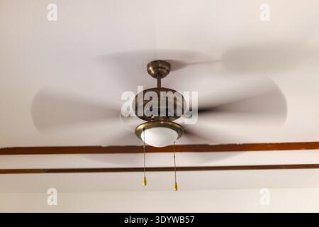 Ceiling fan spinning on white ceiling with built in light fixture in residential interior Stock Photo