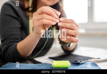 Woman Sewing At Home Threading A Needle In A Close-Up Of Hand Stock Photo