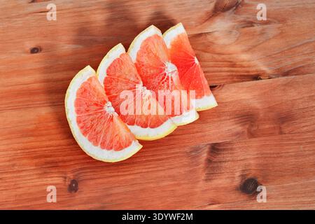 Slices of pink  ripe grapefruits ready for eating or cooking on wooden table Stock Photo
