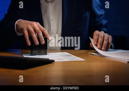 businessman stamping documents on the desk in dark office Stock Photo