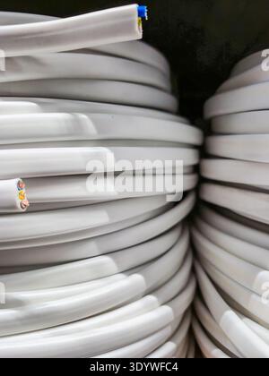Organized rolls of white electrical cables await installation or use in various projects Stock Photo