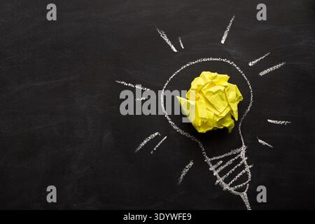 Electric bulb drawn on chalkboard with yellow paper for glowing light Stock Photo