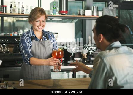 Smiling barista taking payment from client Stock Photo