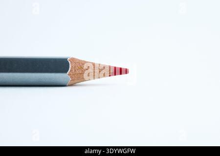 A single grey-barreled red colored pencil lying horizontally on a bright white surface Stock Photo