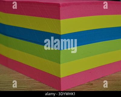 Close-up of a stack of colorful neon sticky notes on a wooden desk. Stock Photo