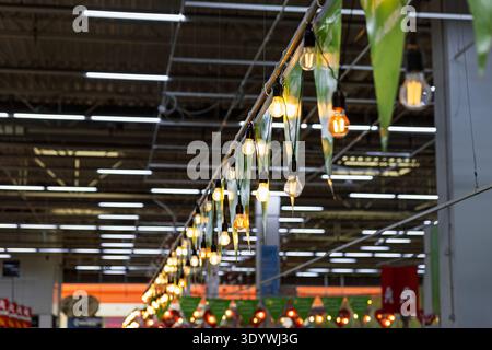 String of Edison light bulbs and green pennants in a supermarket. Stock Photo