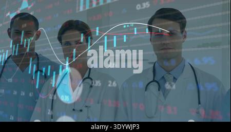 Standing three clinicians wearing lab coats and stethoscopes in clinic hallway showing market data Stock Photo