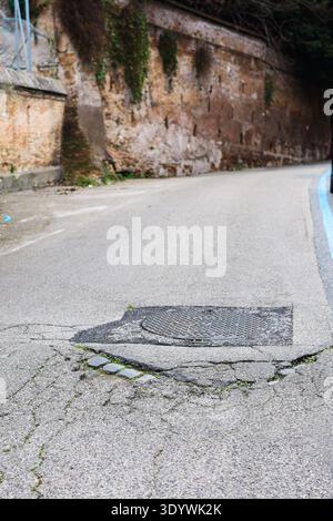 Broken city street pavement around sewer manhole. Urban infrastructure problem. Stock Photo