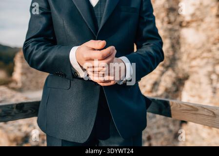 Close-up shot of groom adjusting his sleeve, wearing a wedding ring. Stock Photo
