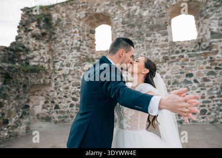 Bride and groom dancing, looking at each other. Wedding couple standing outside near ruins. Bride and groom dancing, looking at each other. Beautiful Stock Photo