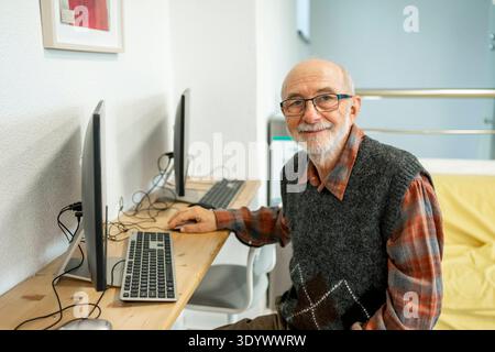 Senior man working on computer at desk. Focused senior man working on computer at desk. model released Stock Photo