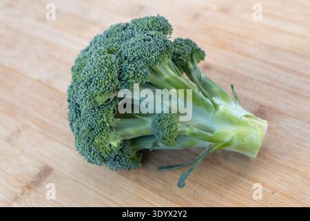 Fresh green broccoli on wooden cutting board. Healthy vegetable ingredient rich in vitamins and fiber. Stock Photo