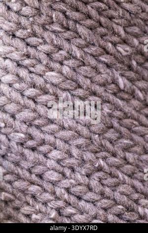 Detailed macro view of knitted wool fabric showing interwoven yarn loops and soft textile texture, suitable as a background or material pattern. Stock Photo