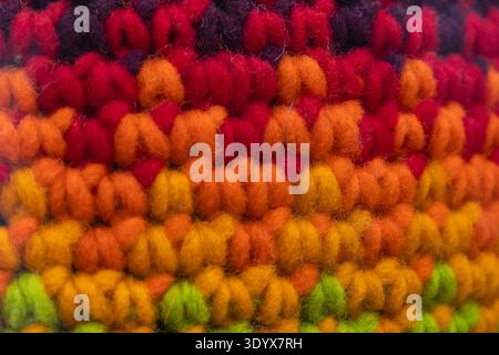 Macro view of vibrant knitted wool fabric showing colorful yarn loops and soft fiber texture, suitable as a textile background or craft pattern. Stock Photo