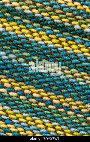 Macro view of woven textile fabric with multicolored threads forming a diagonal striped pattern, showing detailed fibers and artisanal weaving texture Stock Photo