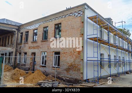 Renovation and repair of an old brick building with large blue metal scaffolding, restoring war damage and improving structure Stock Photo