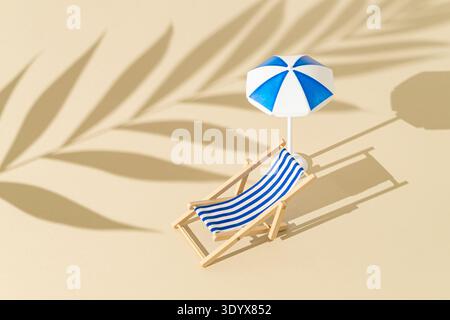 Beach deck and beach umbrella on beige background with tropical palm leaf shadow. Summer vacation concept. Stock Photo