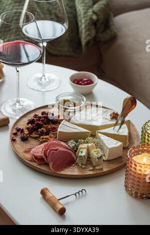 Elegant charcuterie board composition featuring assorted cheeses, cured meats, walnuts, dried cranberries, breadsticks, olives, and red jelly, paired Stock Photo