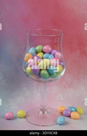 Tiny Easter eggs in wine glass and on the table. Vertical photo with copy space. Stock Photo