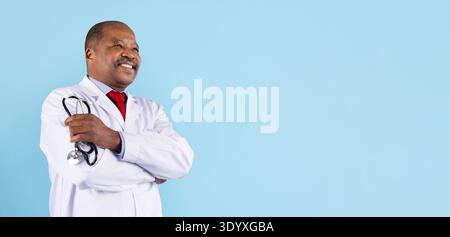 Portrait of confident mature black doctor with stethoscope posing on blue background Stock Photo