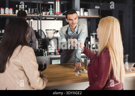 Smiling barista taking payment from clients Stock Photo