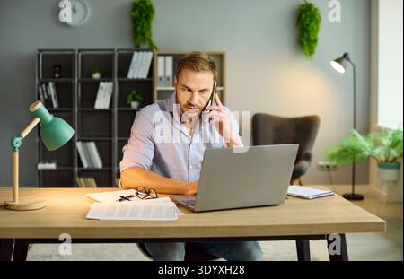 Business man talking by phone working on workplace with laptop in office. Stock Photo