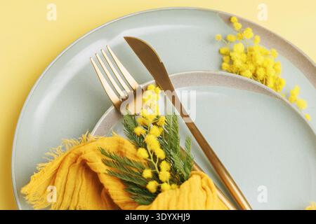 Spring Table Setting with Mimosa Flowers and Golden Cutlery Stock Photo