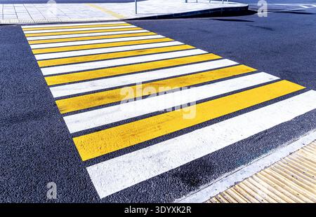 Pedestrian crossing with white and yellow stripes as background. Crosswalk of white-yellow color on the asphalt road Stock Photo
