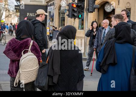 Three Muslim women wearing traditional Hijab head covering on a busy street in Oxford city centre, England, UK Stock Photo