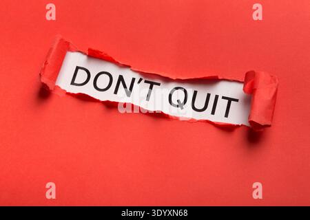 Dont quit phrase bursting out from torn red paper Stock Photo