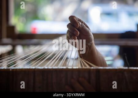 Close-up of a hand holding a silk thread on a loom in a handicraft shop, Luang Prabang, Laos, Asia Stock Photo