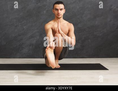 Young flexible man practicing yoga at gym Stock Photo