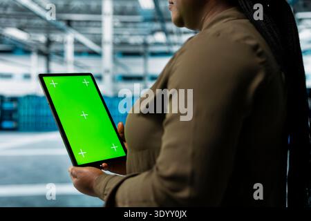 Data center software developer using green screen tablet to automate anomaly detection. Server hub IT professional using chroma key device, minimizing downtime through predictive maintenance Stock Photo
