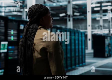 IT professional walking in data center with mainframes supporting business needs. Server room employee doing checkup, ensuring electronics work at optimum performance for smooth operations Stock Photo
