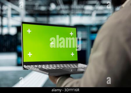 Close up of technician using green screen laptop in high tech data center to check for server performance issues. Server hub workplace employee fixes errors slowing down hardware using mockup notebook Stock Photo