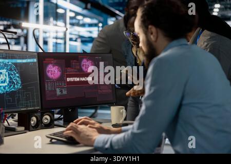 Close up of data center admins reacting to virus alert on PC monitor, initiating protocol to protect critical systems. Server room coworkers review hacking attempts and assessing compromised gear Stock Photo
