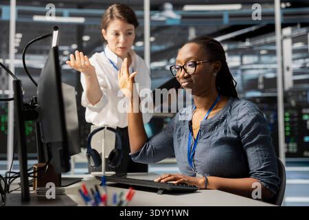 Data center engineer doing talk to the hand gesture, being dismissive of coworker berating her, reproaching performance issues. Ignorant worker in server farm ignoring verbal reprimand from colleague Stock Photo