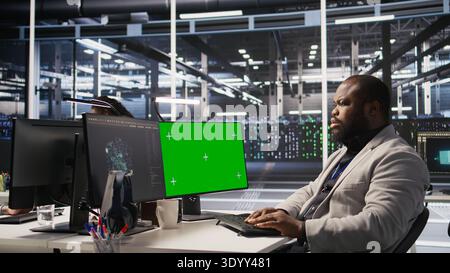 Data center admin using isolated screen PC to monitor neural network AI. Server room employee using mockup computer to oversee rigs powering machine learning processes, camera A Stock Photo
