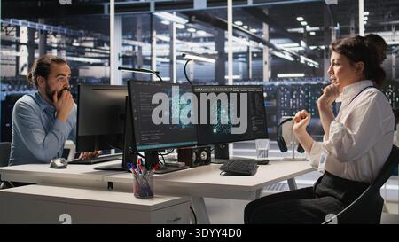 Cheerful data center engineers dancing in excitement in office chairs after successful AI deployment. Smiling server room colleagues celebrating achievement, reaching performance goals, camera A Stock Photo